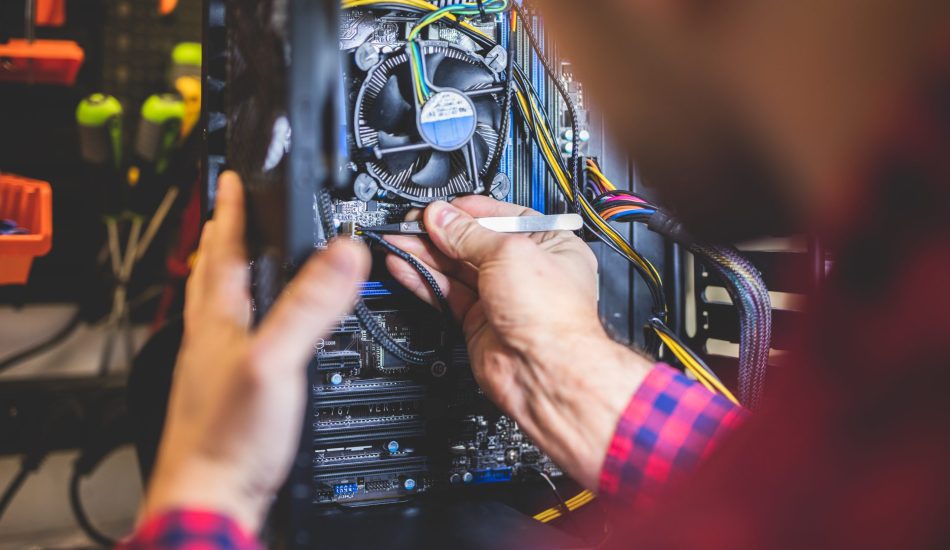 Man fixing PC in professional workshop. IT service and engineering. Electronical device.